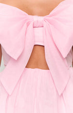 Close-up of the back of a pink mini dress showing a large sheer bow, a cutout detail, and the top of the tulle skirt