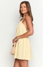 Side view of the yellow halter mini dress showing the loose, flowy fit and mini length