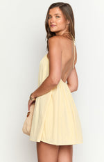 Side view of a yellow halter mini dress showing the open back and tie-neck detail