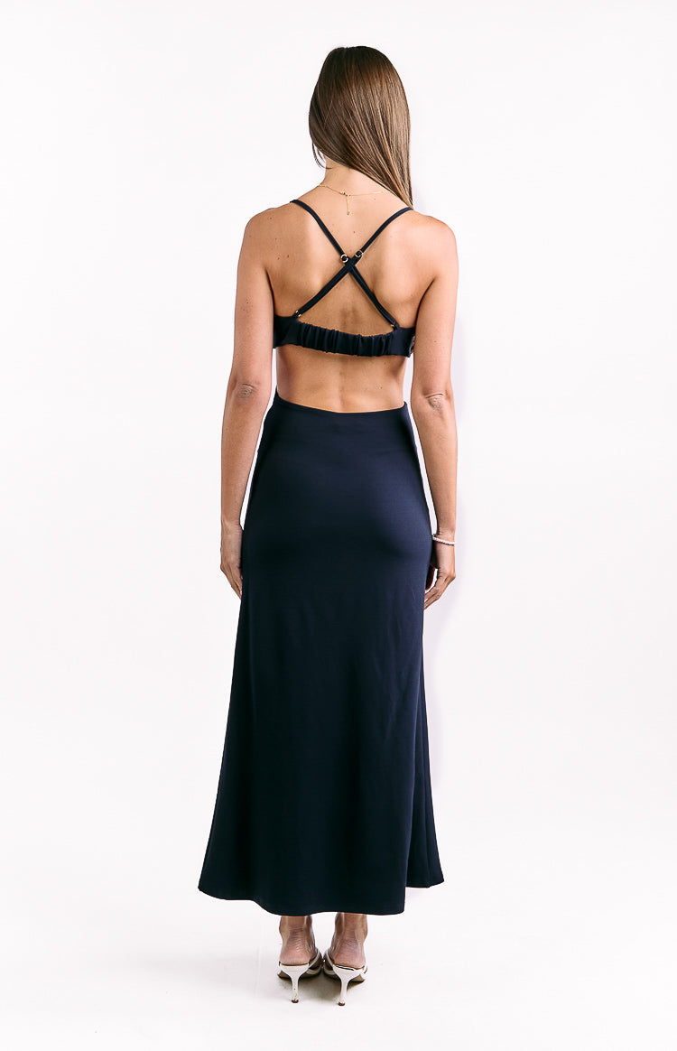 Rear view of a navy crepe maxi dress with criss-cross spaghetti straps, a shirred elastic back, and waist cutouts