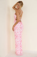 Side view of a pink sequin maxi dress with floral embroidery, waist cutouts, and criss-cross tie-back straps