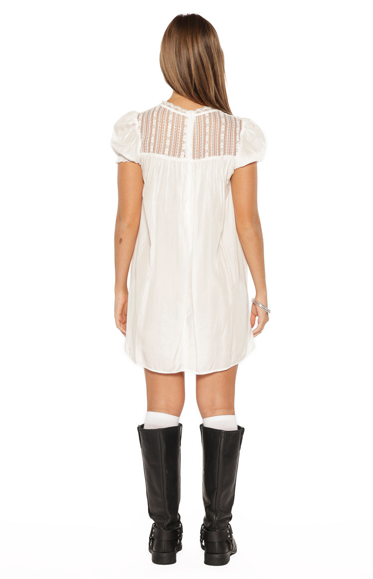 Rear view of the white mini dress featuring a sheer lace panel across the upper back and short puff sleeves