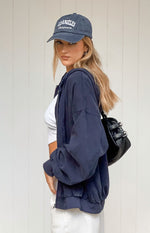 Side view of a washed navy oversized hooded jacket with a front zipper and elasticated cuffs
