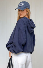 Rear-side view of a washed navy oversized hooded jacket with dropped shoulders and voluminous sleeves