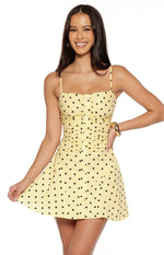 Front view of a yellow polka dot mini dress with a ruched bodice and button-front detail