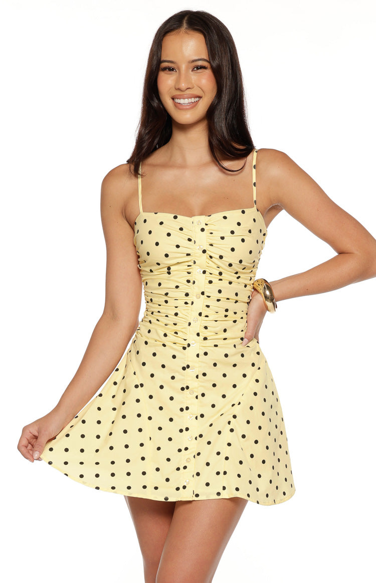 Front view of a yellow polka dot mini dress with a ruched bodice and button-front detail