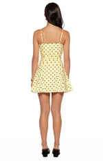 Rear view of a yellow polka dot mini dress with thin spaghetti straps, a ruched back bodice, and a flared skirt