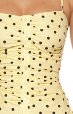 Close-up of the vertical ruching and clear button-front placket on the yellow polka dot mini dress