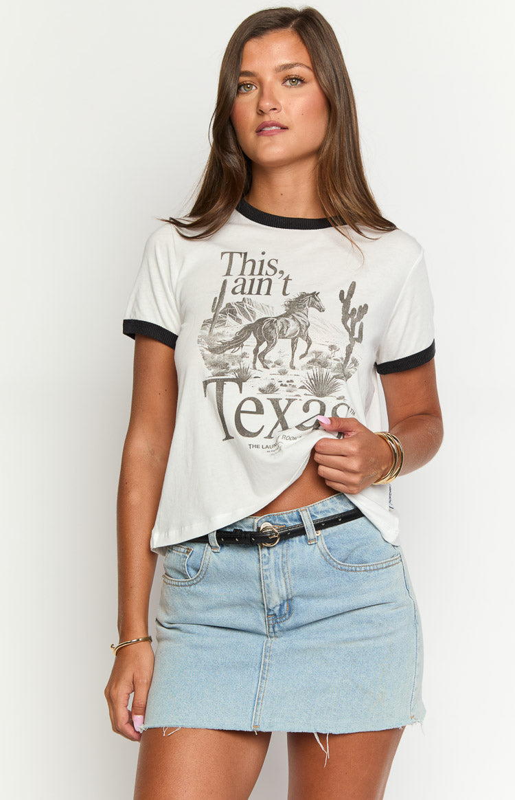 White ringer tee with a "This ain't Texas" graphic print of a horse and desert scene, showing the cropped hem