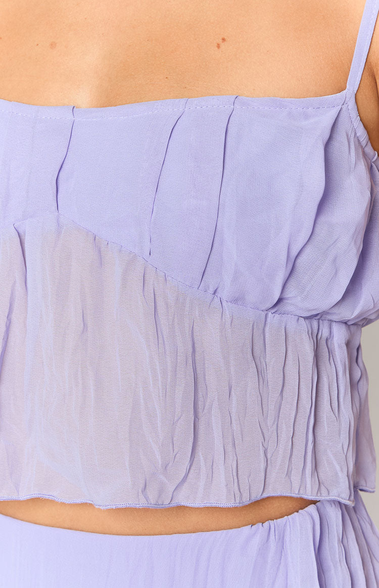 Front view of a cropped purple cami top with a ruffled sheer overlay, square neckline, and thin spaghetti straps