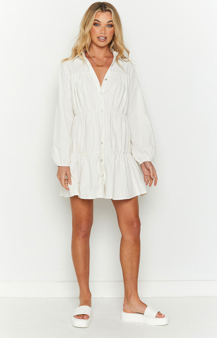 White button-front mini dress with a collared V-neck, long sleeves, and gathered tiered skirt