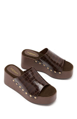 Angled view of two chocolate brown croc-embossed PU wedge sandals with gold stud details and dark brown footbeds