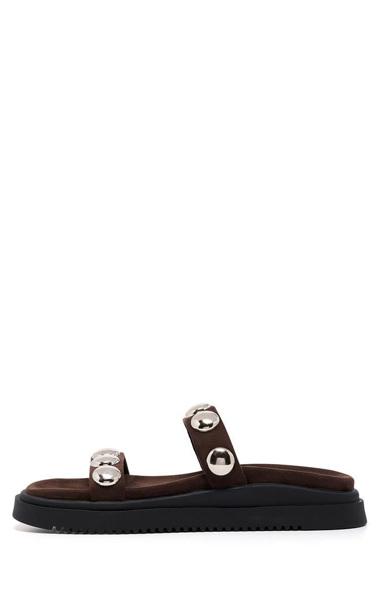 Side view of chocolate suede platform sandals with two straps, each featuring two large silver studs, on a black ridged sole