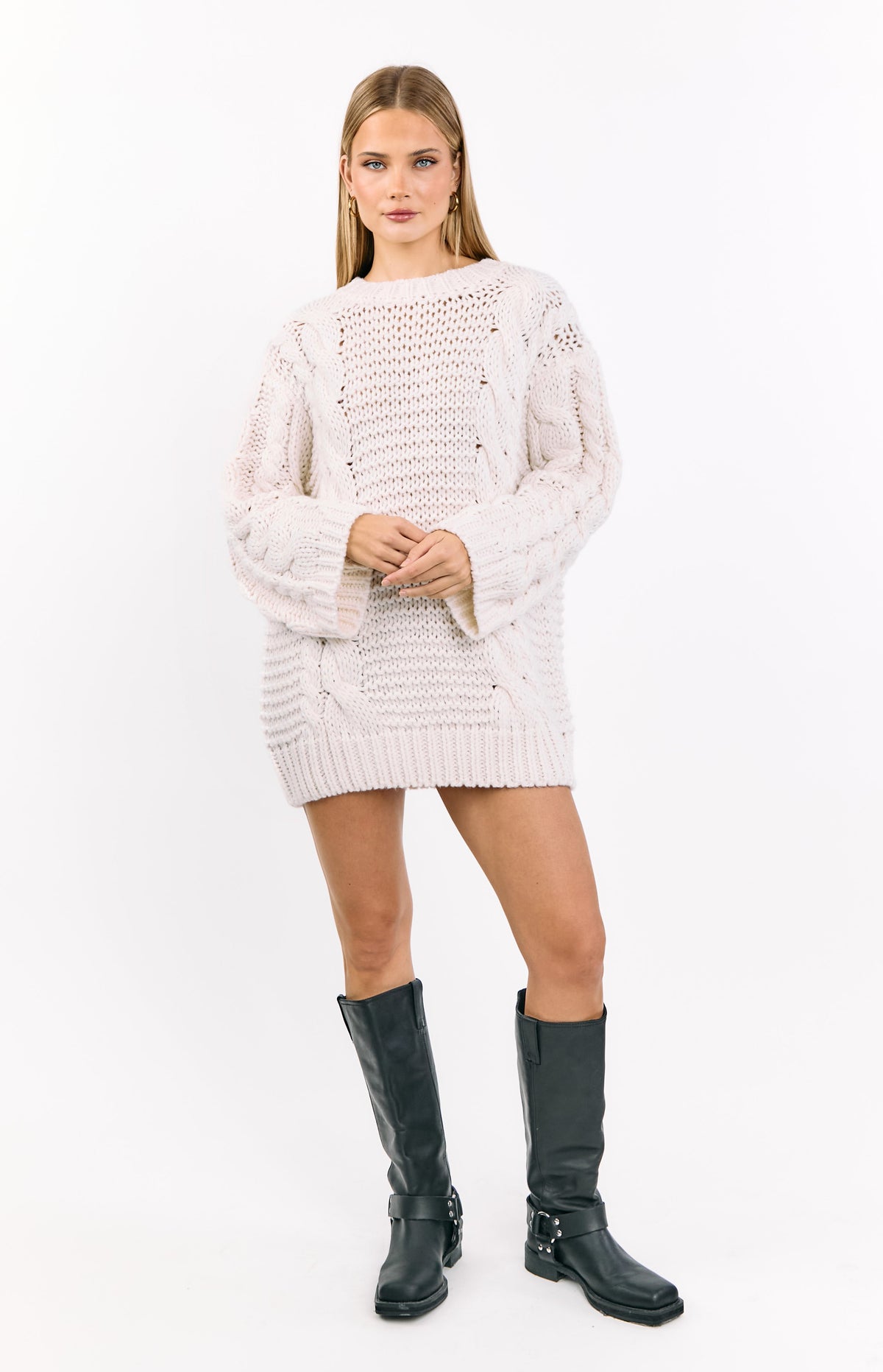 Cream cable knit sweater dress with an oversized fit, wide sleeves, and prominent open knit details
