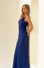 Side view of a navy formal maxi dress showing the cowl neckline, thin spaghetti straps, and ruched side detail