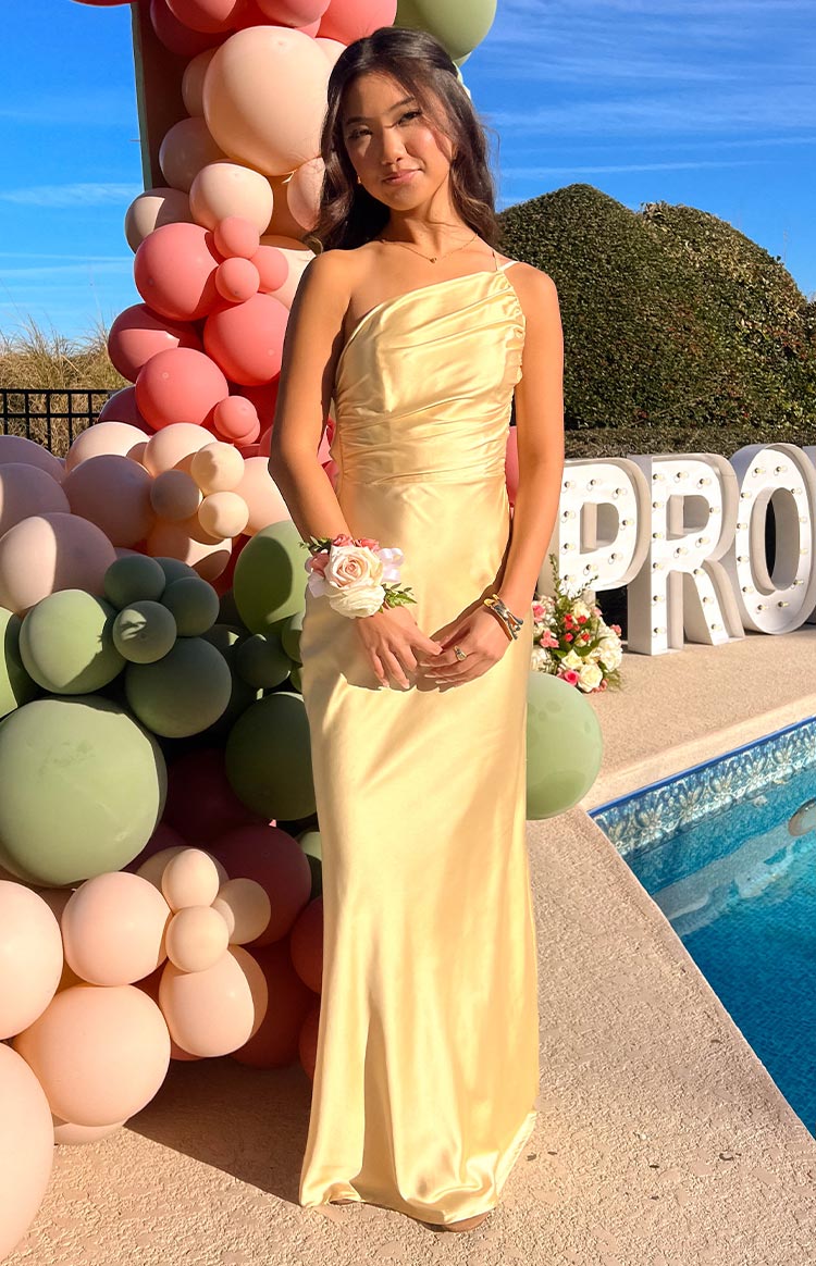 Side view of a yellow satin maxi dress showing the low back, thin spaghetti straps, and ruched side detail