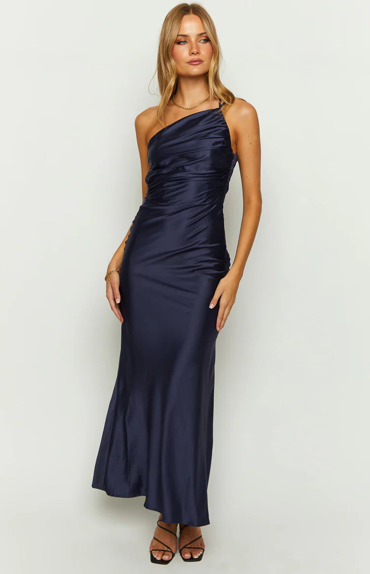 Front view of a navy satin maxi dress featuring a one-shoulder neckline and ruched detailing on the bodice