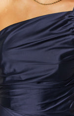 Close-up of the navy satin one-shoulder neckline and ruched bodice of a formal maxi dress