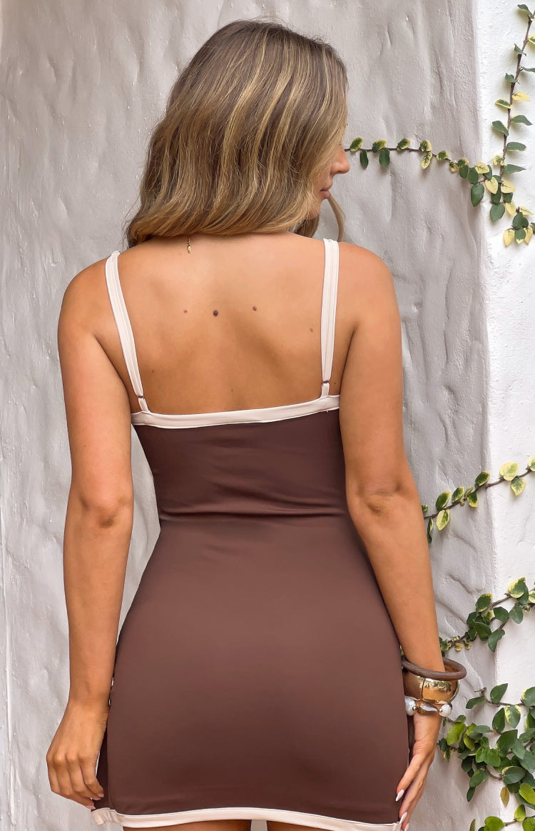 Rear view of a chocolate brown mini dress with thin cream spaghetti straps and cream trim