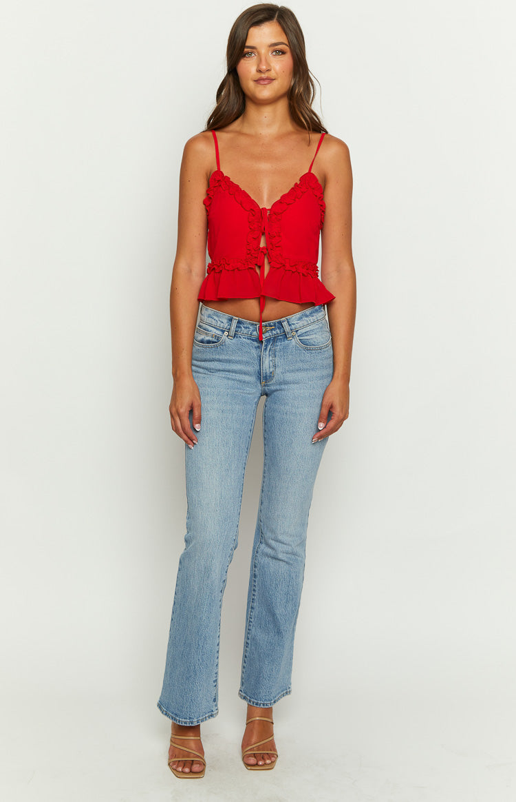 Front view of a red cami with frill trim V-neckline, tie-front, spaghetti straps, and a ruffled cropped hem
