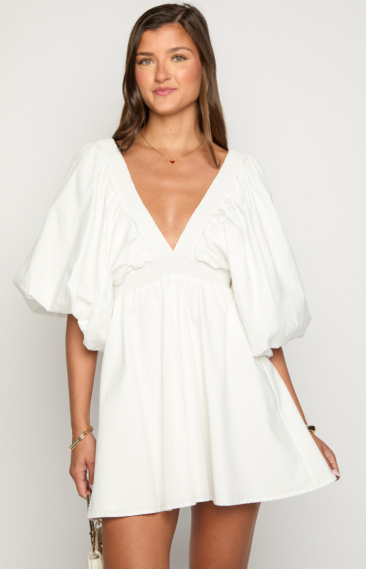 Front view of a white mini dress with a deep V-neckline, shirred bodice, and voluminous puff sleeves
