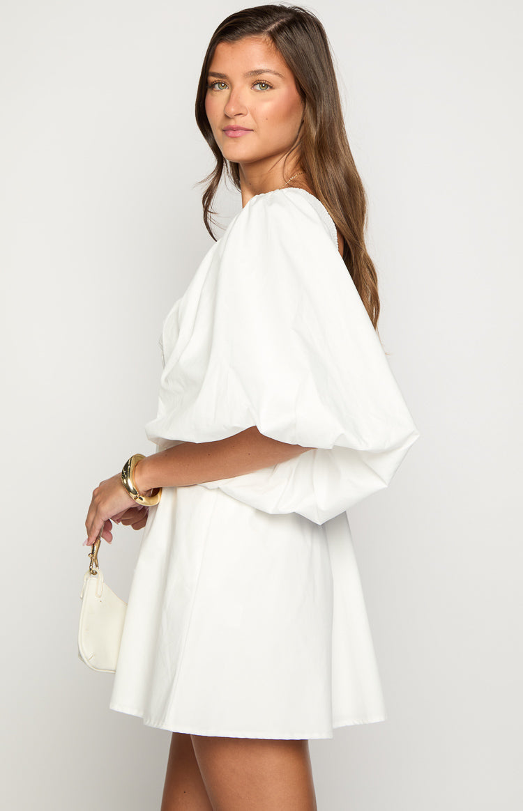 Side view of a white cotton mini dress with voluminous puff sleeves and a flared skirt