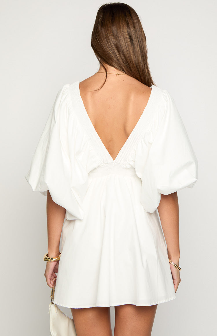 Rear view of a white mini dress with a deep V-back, shirred detailing, and voluminous short sleeves