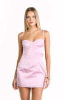 A close-up of a light pink satin mini-dress with thin spaghetti straps a sweetheart neckline and a lace trim on the cups. Our dress has visible seams on the bodice.