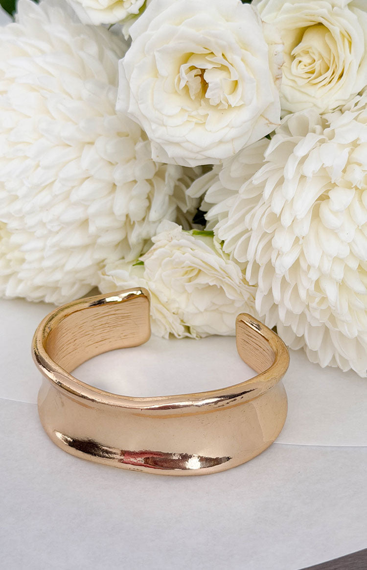 Gold wavy cuff bangle with a wide, open design and a subtle brushed texture on the inner surface