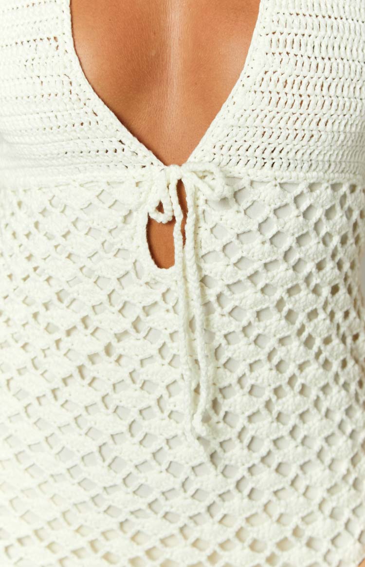 Rear view of a cream crochet mini dress with halter neck ties and an open back with tie closure