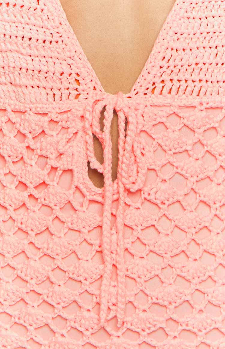 Angled front view of a tulip pink crochet mini dress with a deep V-neck halter and tie-front detail
