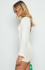 Side view of a white crochet mini dress with long sleeves and an open back detail