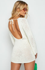 Rear-side view of a white crochet mini dress with a deep backless design and a tie closure at the neck
