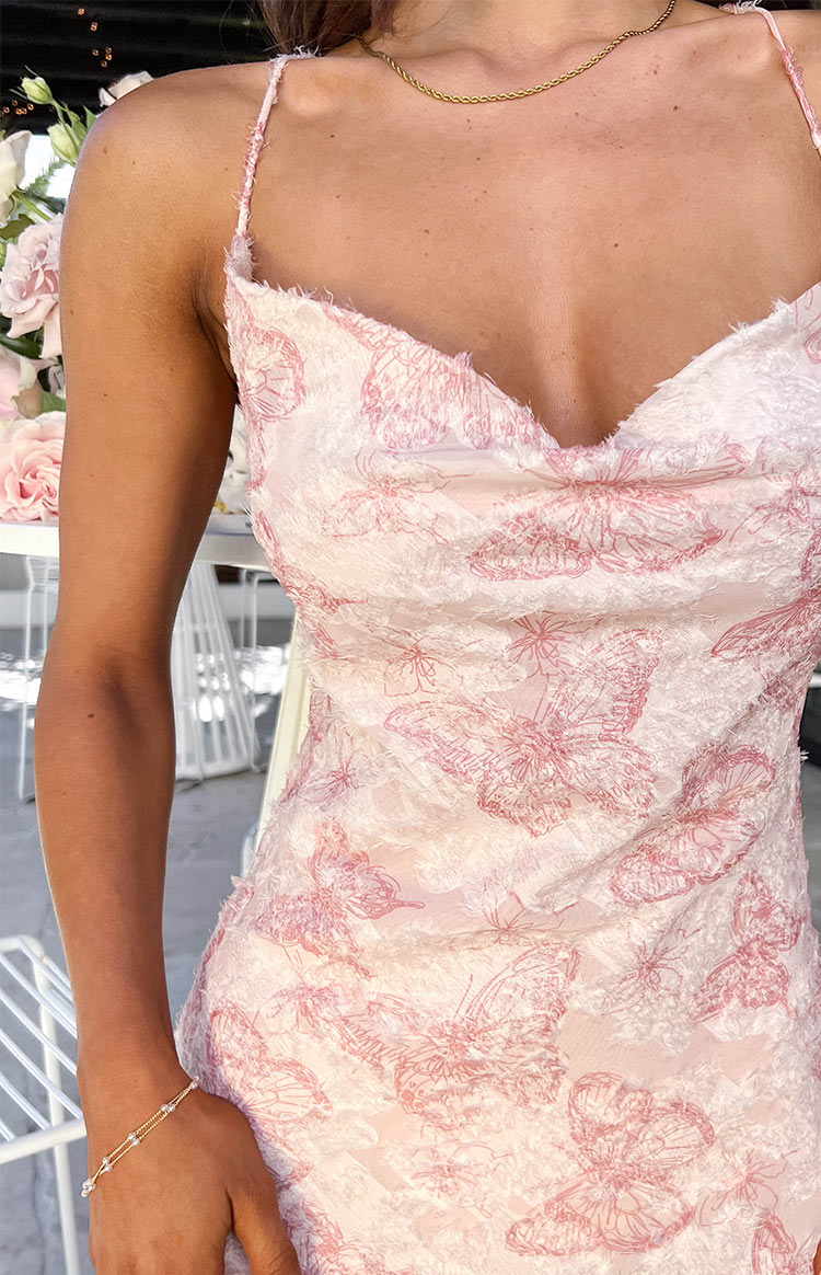 Close-up of the pink maxi dress fabric featuring raised white and embroidered pink butterfly patterns