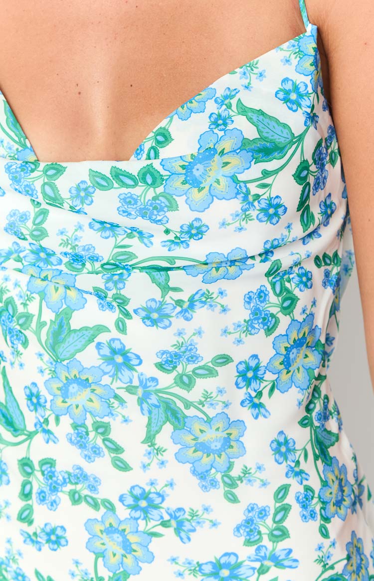 Close-up of the blue floral print, cowl neckline, and thin spaghetti strap on a white maxi dress