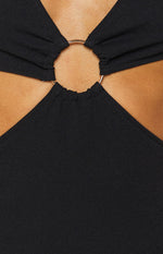 Black textured dress with a gold O-ring detail connecting gathered fabric panels and chest cutouts