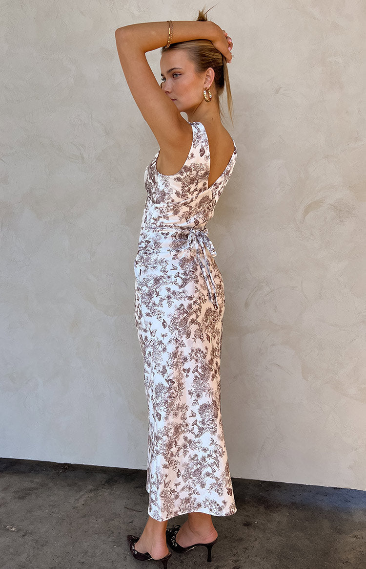 Side view of a white and brown garden print maxi dress with a tie-back detail and V-neck back