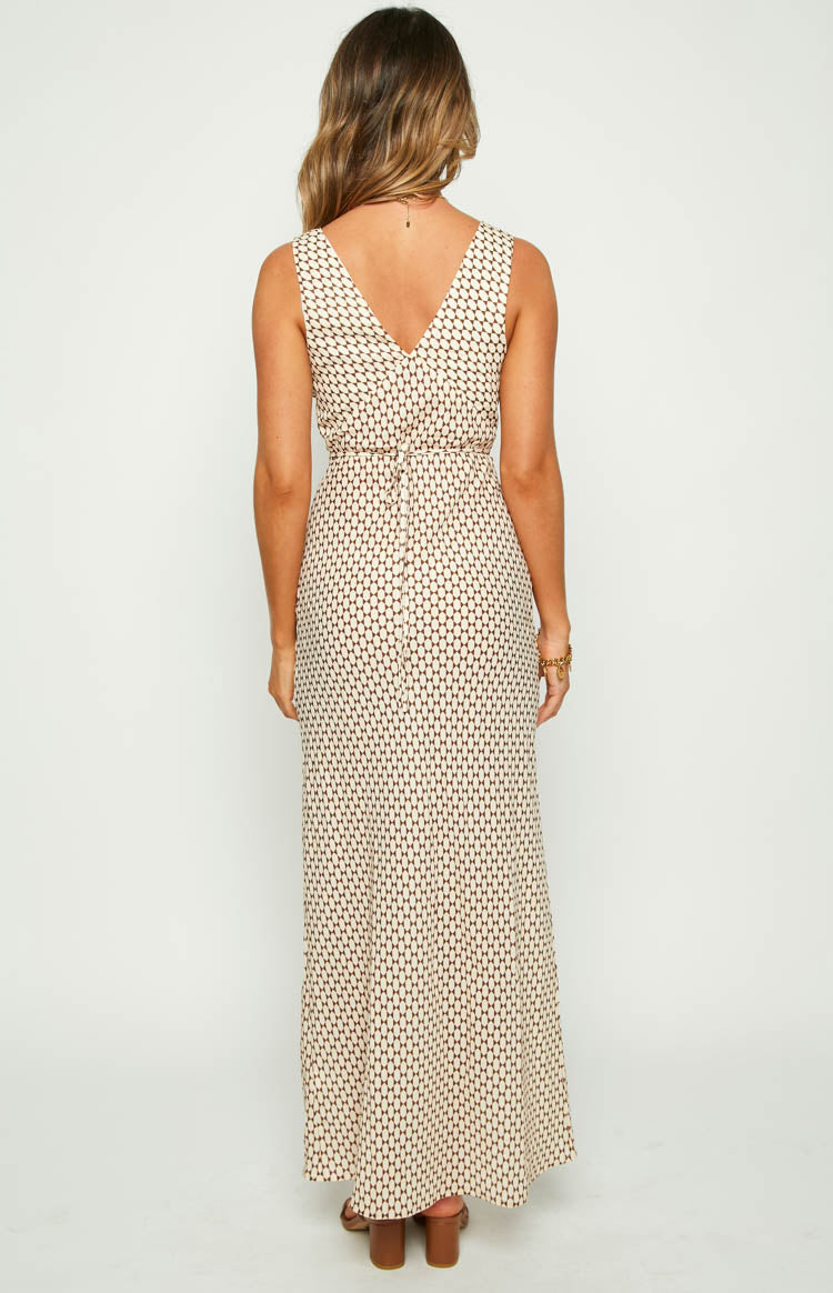 Back view of a beige maxi dress with a brown geometric pattern, showing the V-neck and a tie detail at the waist