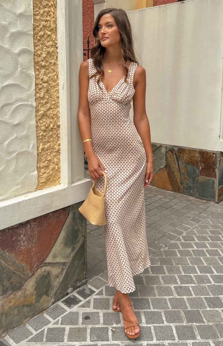 Full length view of a fitted beige maxi dress with a small brown geometric pattern and deep V-neck