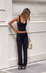 Black low waist pants with a straight leg fit and button details at the front waist