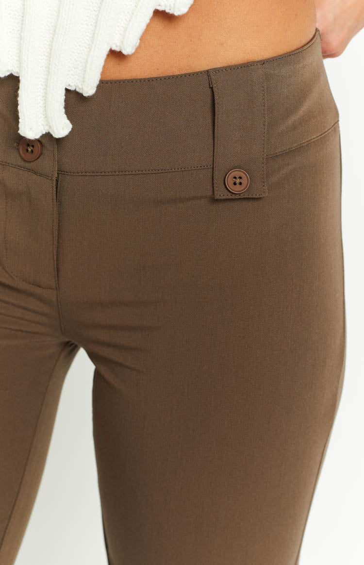 Close-up of the low waist and button closure detail on taupe pants