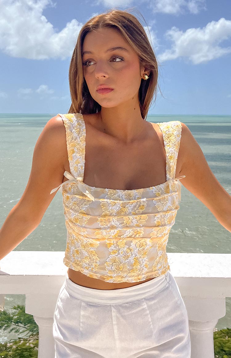 Rear view of a yellow and white floral lace crop top with a square back and wide straps