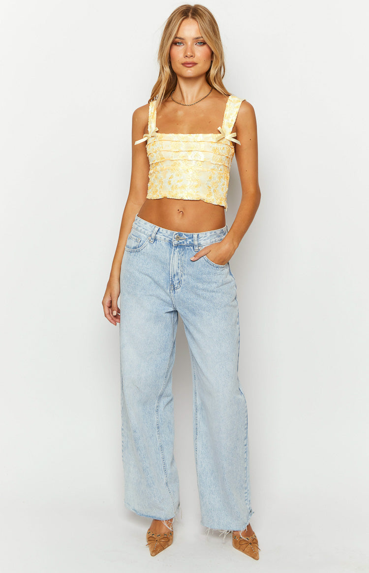 Front view of a yellow lace crop top with square neckline and bow details on the shoulder straps