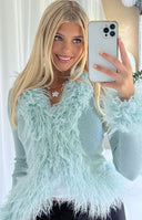 Close-up of the mint green ribbed knit cardigan with shaggy fur trim on the V-neckline and cuffs