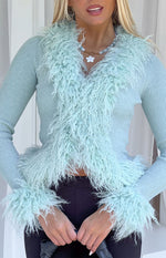 Close-up of the mint green ribbed knit cardigan with shaggy fur trim on the V-neckline and cuffs