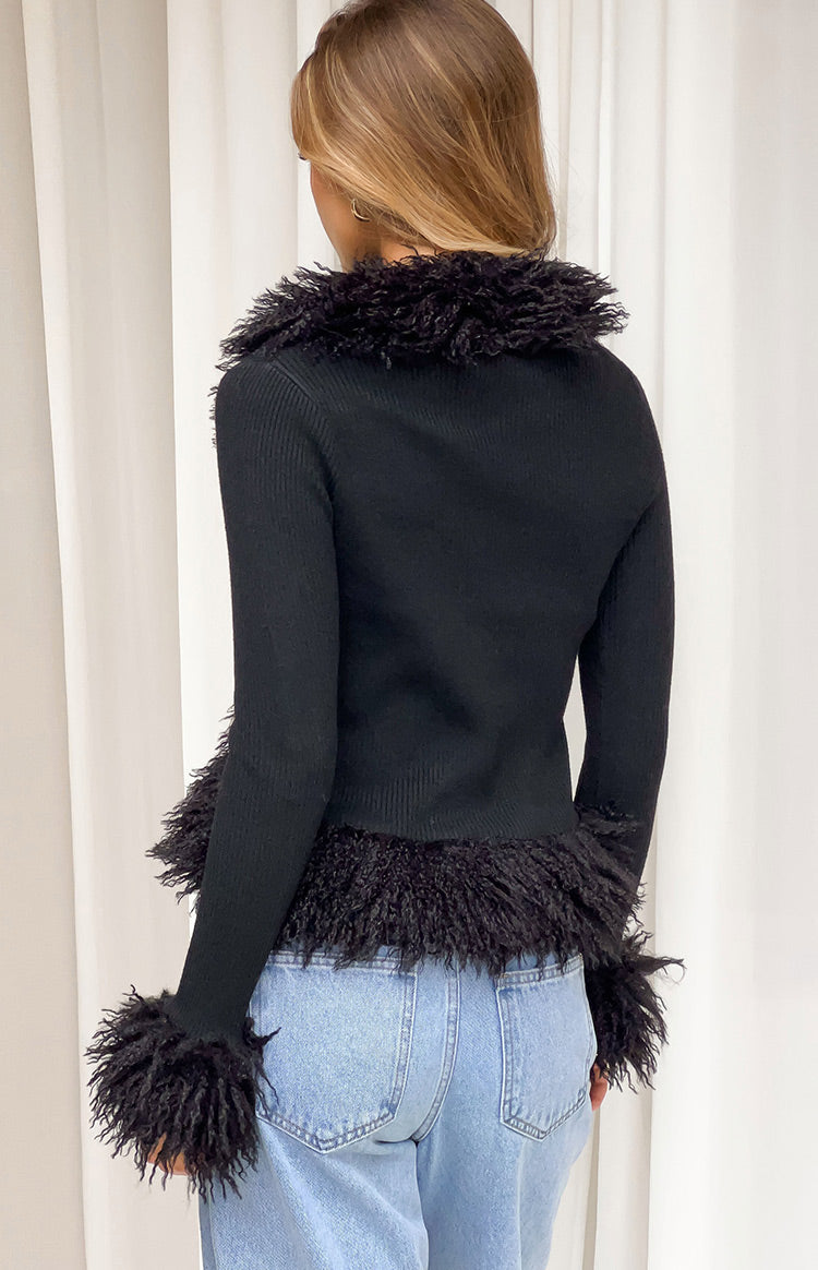 Rear view of a black ribbed knit cardigan with shaggy fur trim on the collar, hem, and cuffs