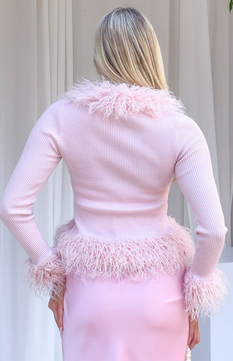 Rear view of a pink ribbed knit cardigan with fluffy fur trim on the collar, hem, and sleeve cuffs