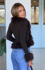 Side view of a chocolate ribbed knit cardigan with shaggy fur trim on the collar, cuffs, and hem