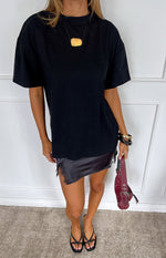 Front view of a black satin mini skirt with an asymmetrical hem and delicate black lace trim