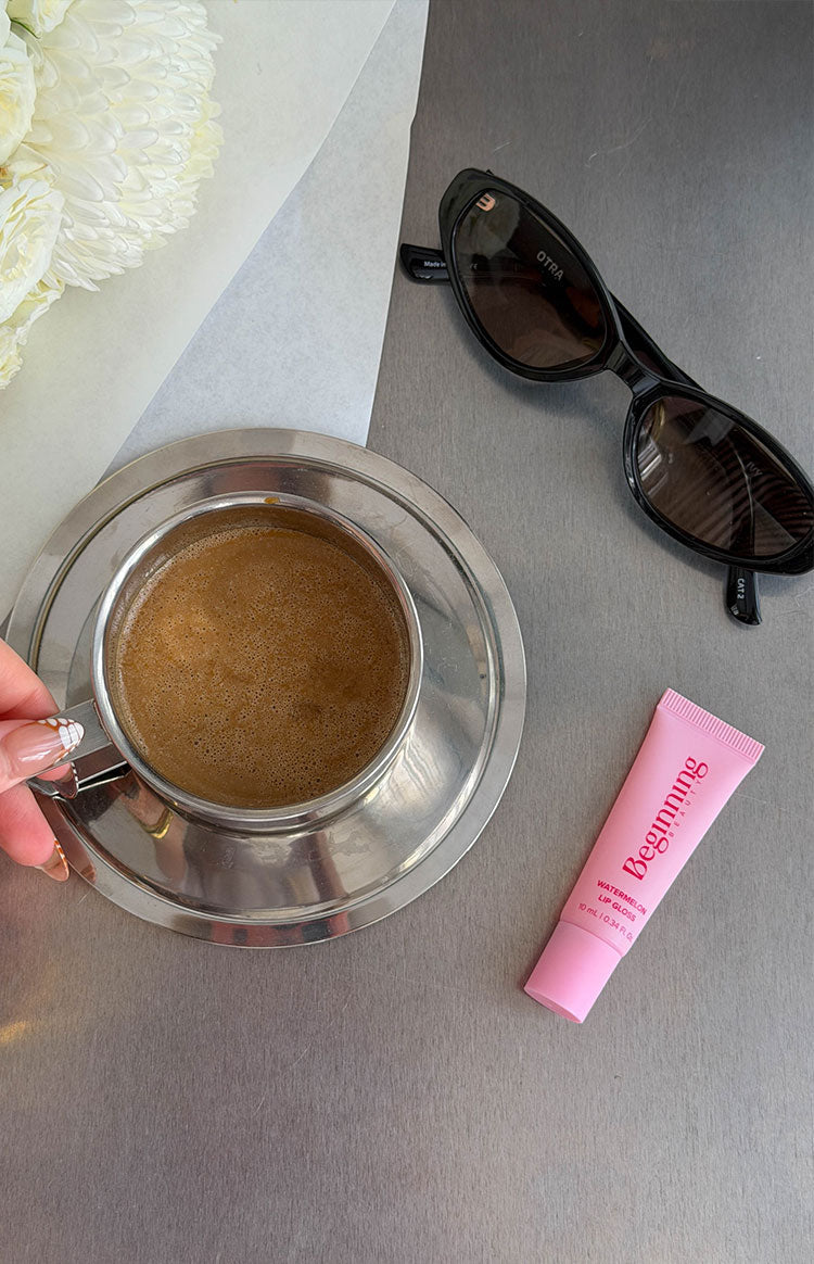 Pink lip gloss tube with white descriptive text and volume details